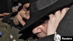 Galliano is surrounded by officers as he leaves a police station in Paris in February 2011.