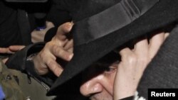 Британский модельер Джон Гальяно в сопровождении полицейских выходит из полицейского участка.Париж, 28 февраля 2011 года.