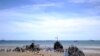 People walk aboard ships set up on the beach in Arromanches prior to a joint French-Dutch D-Day commemoration ceremony on June 6, 2014.