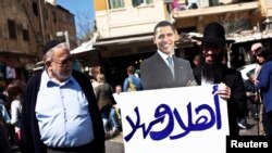 Евреин држи во раката транспарент со ликот на Обама на кој пишува „добредојде“. 
