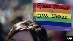 Геј активист го држи знамето с со виножито за време на Парада на гордоста.