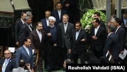 Iranian President Hassan Rouhani (center) alongside parliament speaker Ali Larigani at the August 5 ceremony in parliament in Tehran