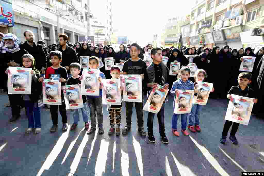 Iranian boys hold images of one of the victims, 4-year-old Mohammad Taha Eghdami, during a public funeral ceremony for those killed in the attack in the southwestern Iranian city of Ahvaz on September 24.