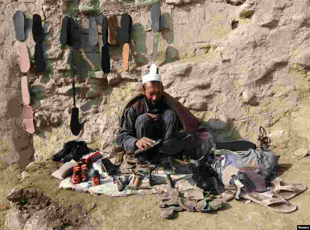 A cobbler sits by the roadside as he brushes a customer's shoes in Kabul. (Reuters/Omar Sobhani) 