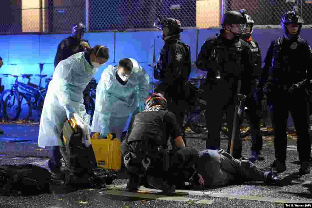 Emergency crews attend an injured man detained by police during a protest in front of the east precinct station, Wednesday, Nov. 4, 2020, in Seattle. 