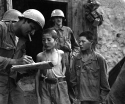 Two boys who were serving in the North Korean Army are interrogated by a U.S. soldier on September 18, 1950.