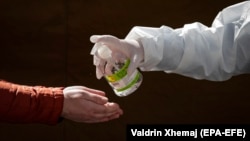 Një punonjës shëndetësor dezinfekton duart e një qytetari. Prishtinë, 6 prill, 2020.
