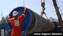 Un muncitor aranjând o țeavă pe șantierul Nord Stream 2, lângă orașul Kingisep, regiunea Leningrad. 5 iunie 2019