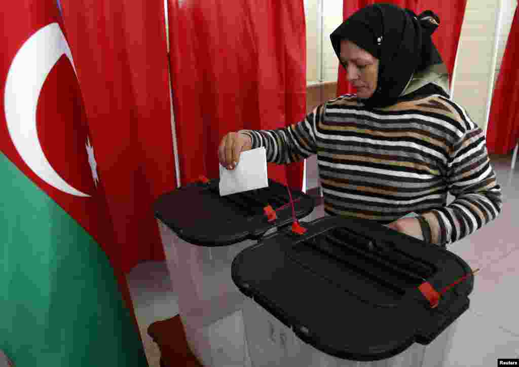 A woman casts her vote during the presidential election at a polling station in Baku.