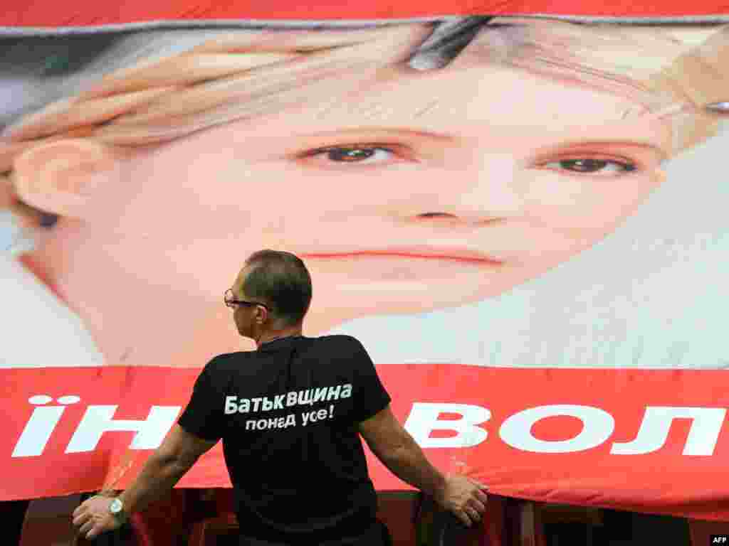 An opposition lawmaker stands next to a giant poster, featuring Yulia Tymoshenko in the Ukrainian parliament in Kyiv on September 6. (Photo by Sergei Supinsky for AFP)