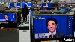 Жапония премьер-министрі Синдзо Абэнің баспасөз мәслихатын дүкенде теледидардан тікелей эфирде қарап тұрған адам. Токио, 20 қаңтар 2015 жыл. (Көрнекі сурет)
