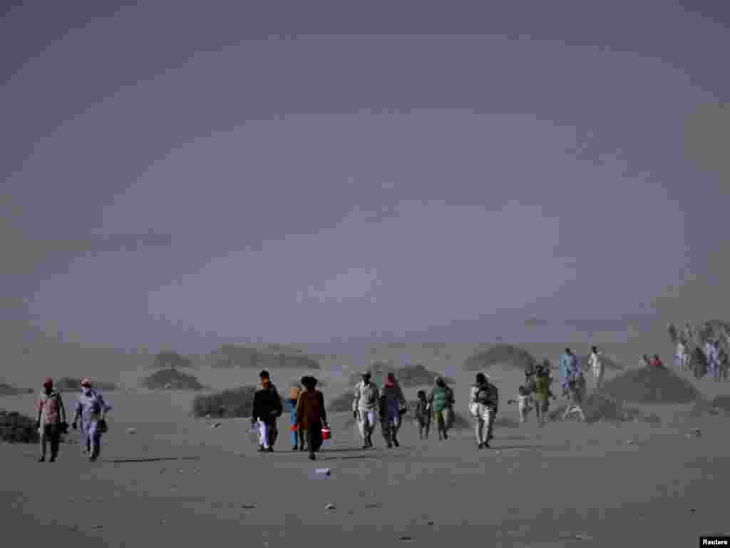 Hindu devotees endure a dust storm while walking by foot for miles towards the Chandargup mud volcano to perform a ritual offering of coconuts in Pakistan's Balochistan Province. Photo by Akhtar Soomro for Reuters.