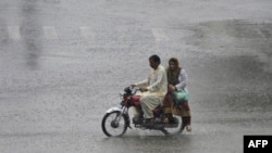 A Pakistani commuter drives his motorcycle through the monsoon rain in Lahore on July 24.