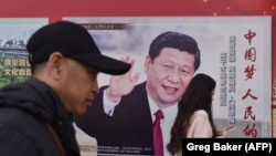 Прохожие у плаката в Пекине с портретом Си Цзиньпина, лидера Китая.