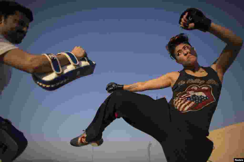 Interior designer Zahra Afridi (right) kicks a punching bag during a kickboxing training session at her home in Islamabad. Afridi runs her own interior design company. Her most recent project was the Classic Rock Coffee café in the Pakistani capital.