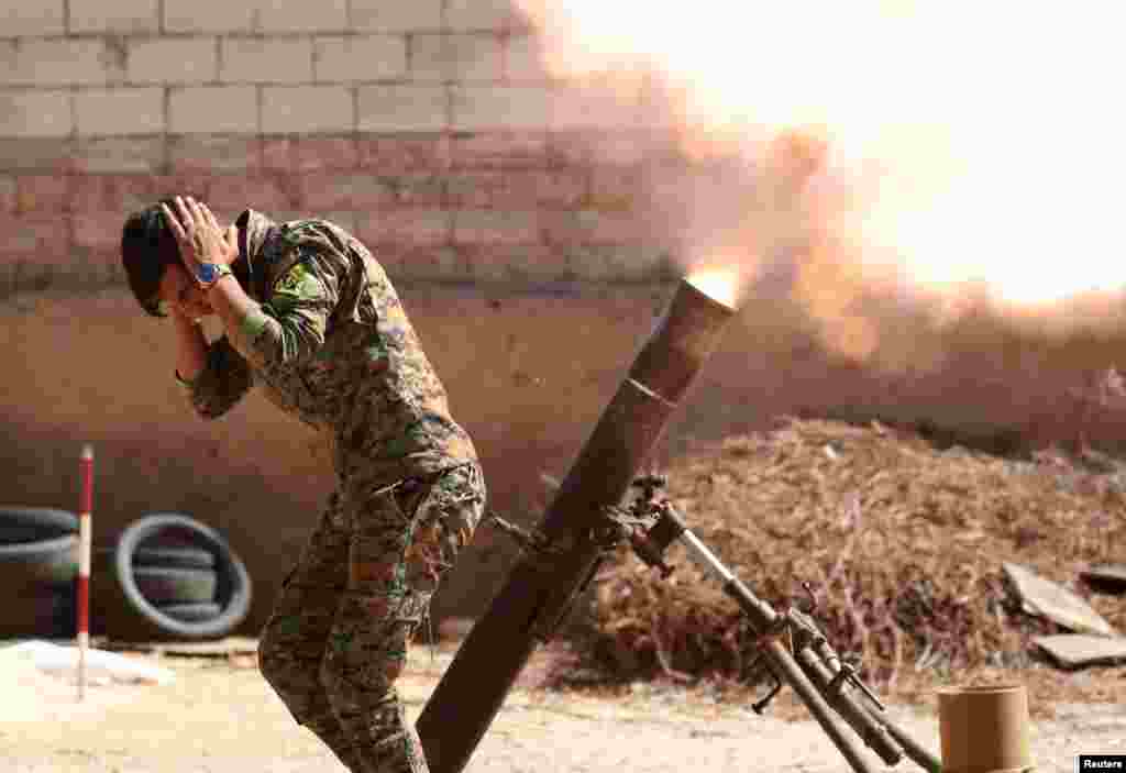 Syria -- A Kurdish fighter from the People's Protection Units (YPG) fires a 120 mm mortar round in Raqqa, June 15, 2017