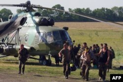A wounded Ukrainian soldier walks with fellow soldiers away from a helicopter on July 31 in a field near Zaporizhya.