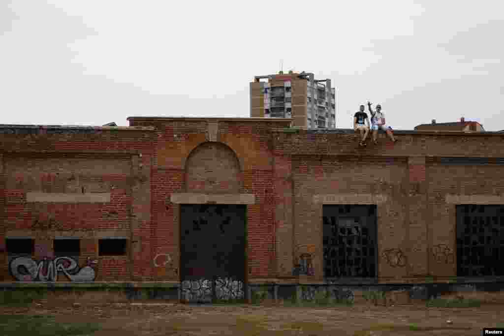 Two boys show the three-finger salute, a symbol of Serbia, as they sit on top of an abandoned manufacturing hall.