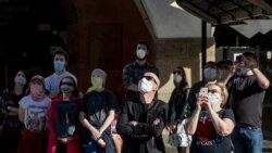 Люди в масках смотрят на Пражские куранты Орлой в Старом Граде.