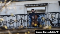 Французский виолончелист Камило Перальта играет на своем балконе в Париже