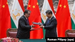 Chinese President Xi Jinping (right) and Tajik President Emomali Rahmon exchange documents during a signing ceremony in Beijing on August 31. 
