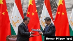 Chinese President Xi Jinping (right) and Tajik President Emomali Rahmon exchange documents during a signing ceremony in Beijing on August 31, 2017.