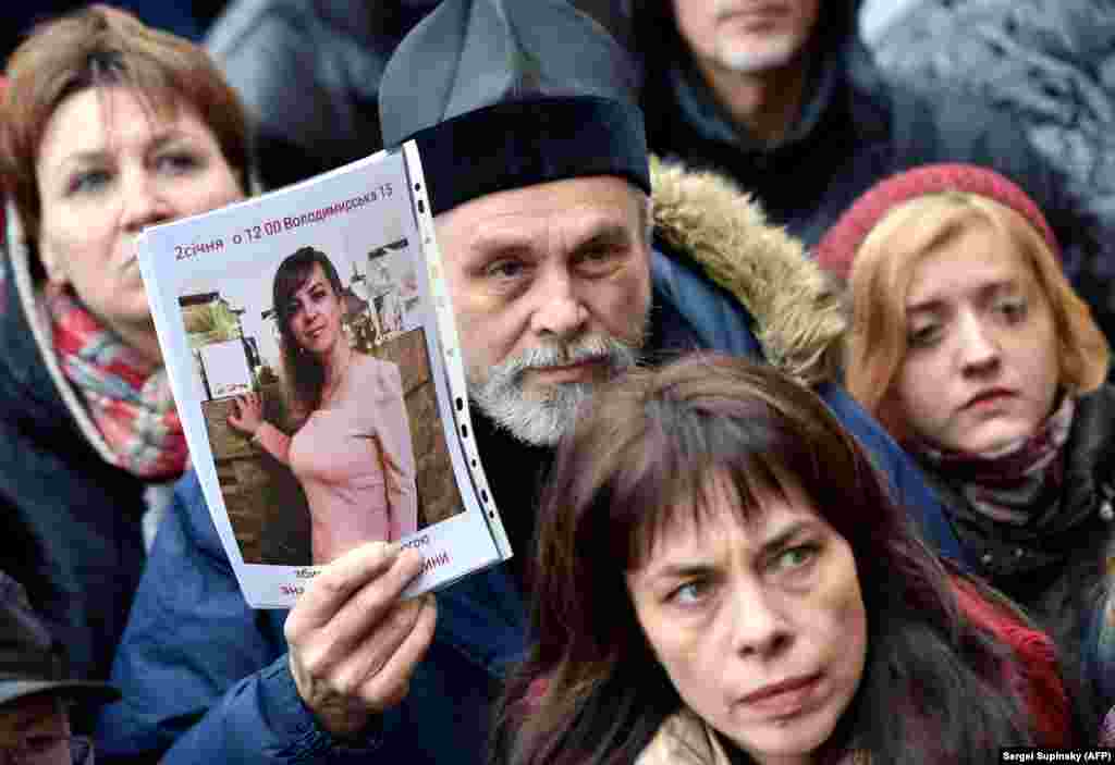 An Orthodox priest holds a picture showing slain Ukrainian lawyer Iryna Nozdrovska as he together with another few hundred activists rally outside the Kyiv police headquarters on January 2. (AFP/Serhey Supinskiy)