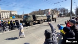 Демонстранти з українськими прапорами скандують «їдьте додому» російській військовій техніці, 20 березня 2022 року