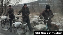 Locals carry bags containing coal that they collected near a coking plant for heating their homes near the government-held industrial town of Avdiyivka.