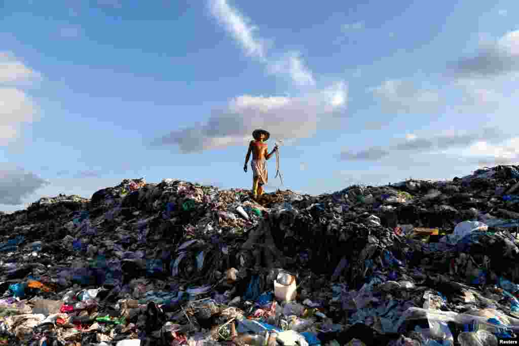 A man walks atop a huge landfill dump as he looks for firewood outside Yangon, Burma. (Reuters/Soe Zeya Tun)