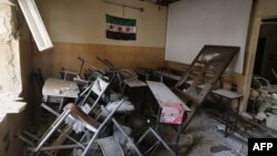 Syria -- A pre-Baath Syrian flag, now used by the Syrian opposition, hangs in a heavily damaged classroom after a barrel bomb hit a school in Syria's northern city of Aleppo Saif al-Dawla district, where control is split between the Syrian regime and opposition.