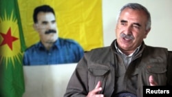 Acting PKK military commander Murat Karayilan in front of an image of rebel leader Abdullah Ocalan