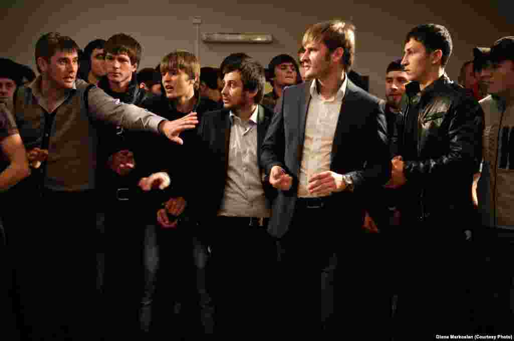 A group of Chechen men at a party stand at the opposite end of the room from the women.