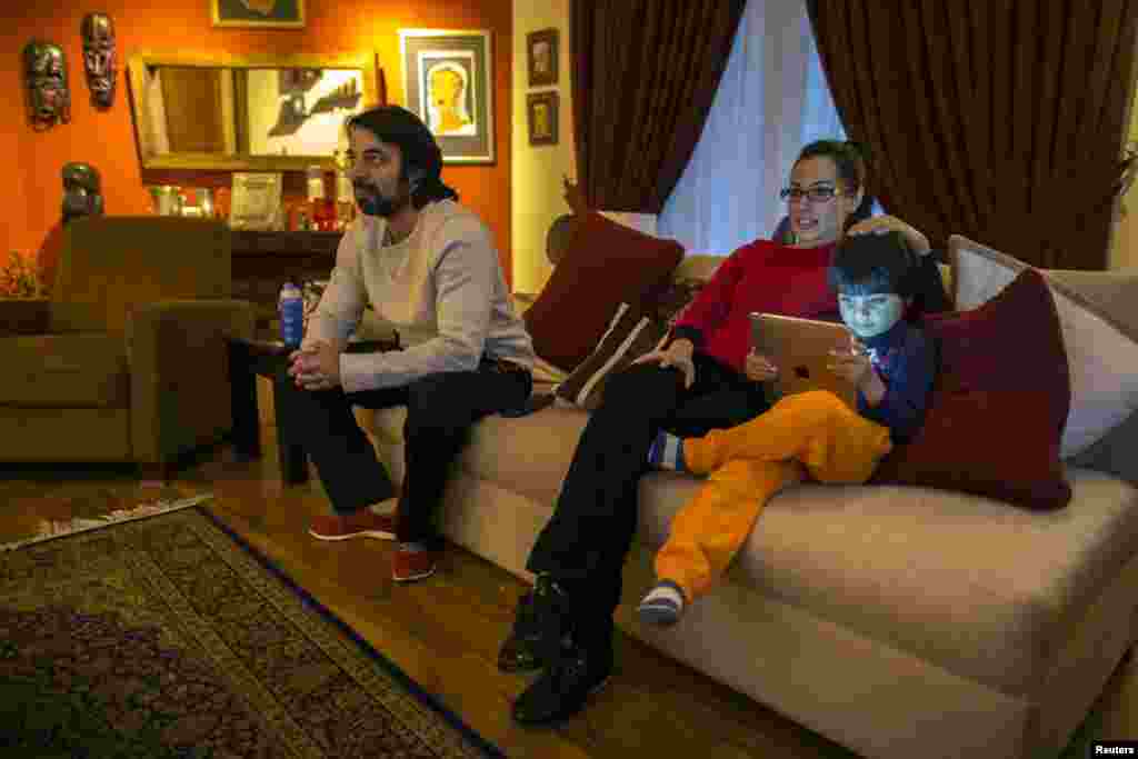 Naadiya Manzur (center), the director of the Treehouse Nursery and Kindergarten, watches television with her husband, Omar, and son, Zidaan, at their home in Islamabad.