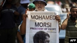 A man holds a portrait of ousted President Muhammad Morsi as thousands of his supporters demonstrate for his reinstatement close to the cabinet headquarters in Cairo on July 17.