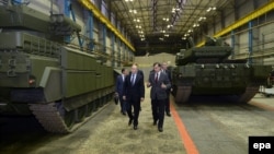 Russian President Vladimir Putin (left) listens to Andrei Terlikov, the head of the Ural Transport Machine Building Design Bureau, as they walk past military vehicles at the Uralvagonzavod factory in Nizhny Tagil, Russia. (file photo)