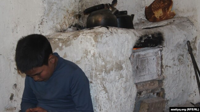 Сын Дильбар Куттыбай греется у печи. Шымкент, 13 марта 2017 года.