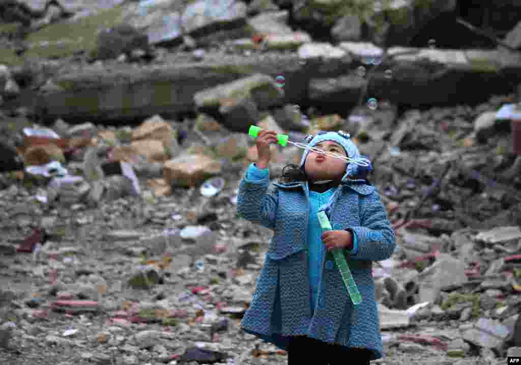 A Syrian girl blows bubbles amid the rubble of destroyed buildings in the rebel-held area of Daraa in southern Syria. (AFP/Mohamad Abazeed)