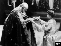 Pe 2 iunie 1953, Arhiepiscopul de Canterbury îi dă Reginei Elisabeta a II-a o spadă, înainte de ceremonia de încoronare.