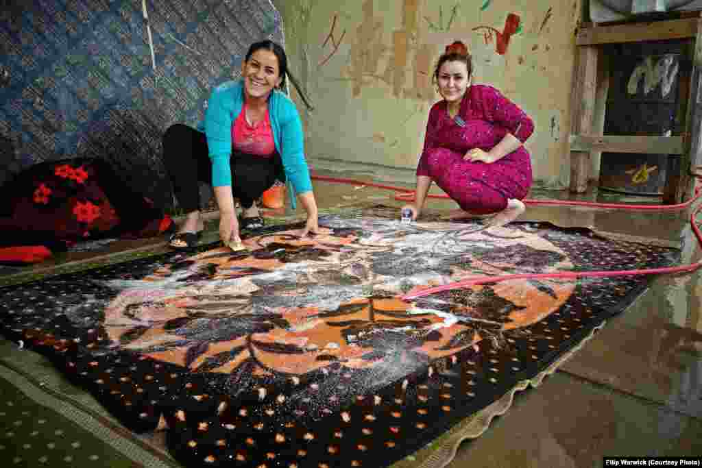 The two-floor compound provides space for up to 270 families. Here, Syrian refugee women clean a carpet used in one of the cells.