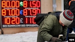 Женщина роется в урне. На заднем плане – курсы валют. Доллар стоит 80 рублей. Москва, 20 января 2016 года. 