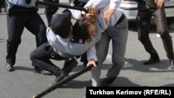 Police and a protester armed with a wooden stick clash in front of the Azerbaijani Education Ministry building in Baku on October 5.