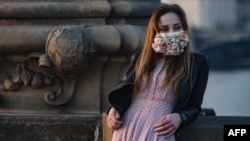 چک از معدود کشورهای اروپایی بود که ماسک زدن در آن اجباری شد. در این عکس، خانمی با ماسک دست‌دوز صورت، روی پل تاریخی چارلز در پراگ دیده می‌شود.