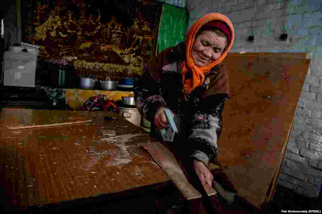 Maria cuts plywood to cover windows shattered by a nearby mortar explosion two days earlier.