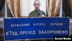 20-летний российский солдат из Саранска Дмитрий Шаров позирует с табличкой погранвойск Украины, взятой в качестве «трофея»
