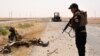 A member of Iraqi government forces inspects a wreckage on the side of a road Qayara Air Base late last month. 