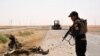 A member of Iraqi government forces inspects a wreckage on the side of a road on June 22, 2016 some 40 kilometers west of Qayyarah.