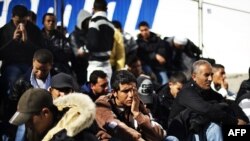 Tunisian immigrants who arrived on the island of Lampedusa wait to board a boat serving as temporary accommodation on February 17.