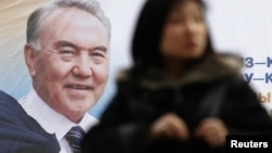 Назарбаевтың суреті салынған билборд тұсынан өтіп бара жатқан әйел. Алматы, 22 ақпан 2011 жыл