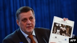 UN Special Representative to Afghanistan Jan Kubis holds up a copy of a report on civilian casualties at a press conference in Kabul on February 8, 2014. 